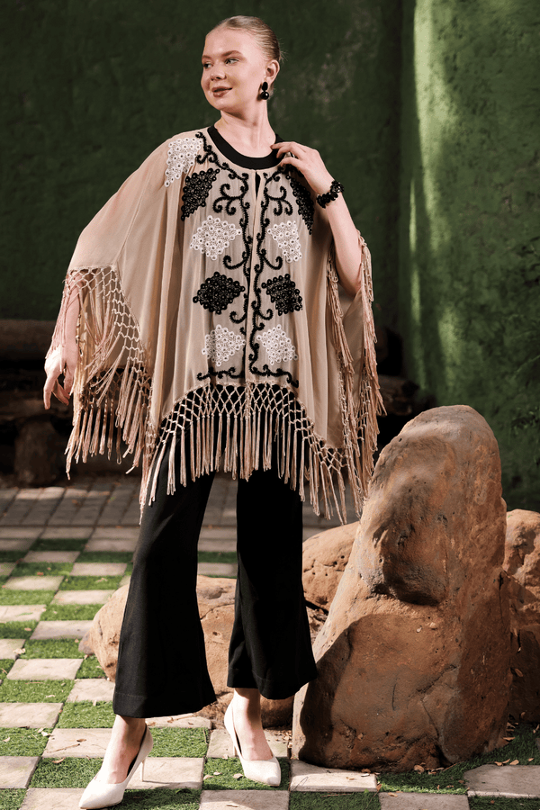 Full view of black and white embroidery detail on beige cape fabric