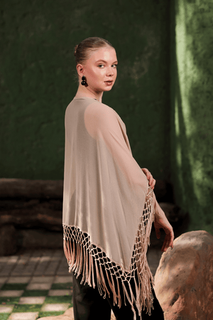 Side profile showing the movement and drape of beige embellished cape with fringe hem
