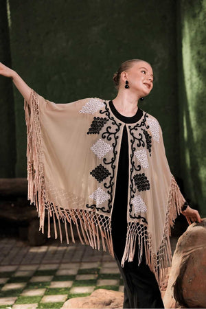 Model in motion wearing beige cape – showcasing fringe movement and sheer texture