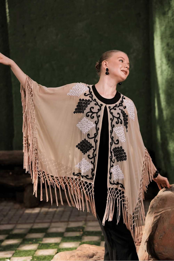 Model in motion wearing beige cape – showcasing fringe movement and sheer texture