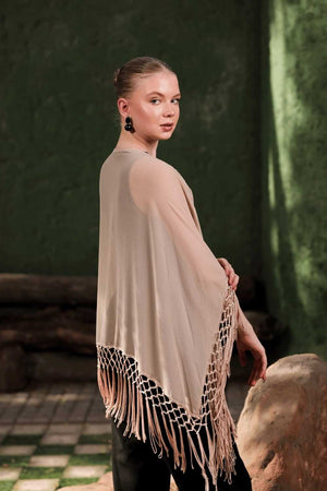 Side profile showing the movement and drape of beige embellished cape with fringe hem