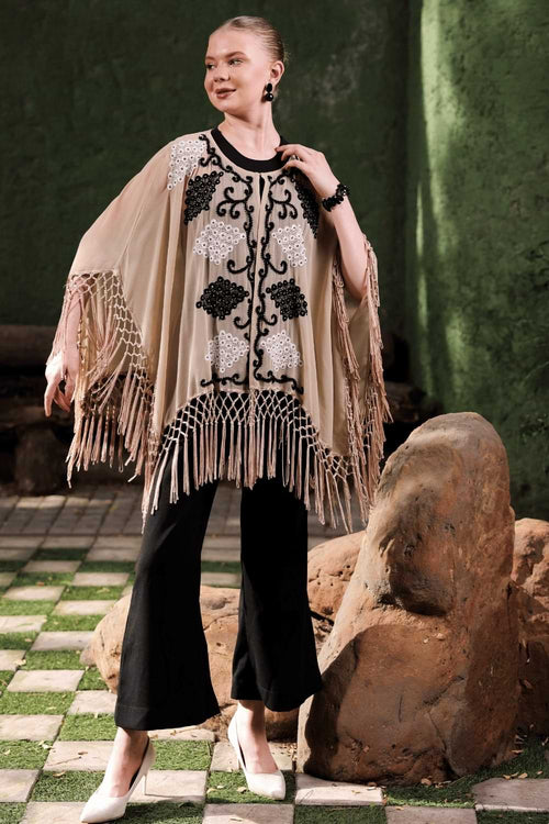 Full view of black and white embroidery detail on beige cape fabric