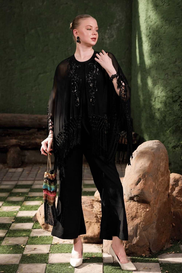Lifestyle shot: woman styling Edition Two black beaded fringe cape over tailored trousers – luxury evening layer India