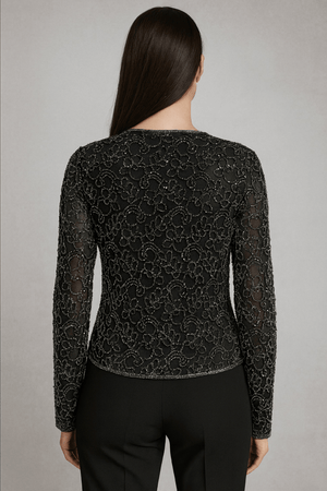 Back view of ivory lace cape paired with black outfit – showcasing embroidery and cape fall