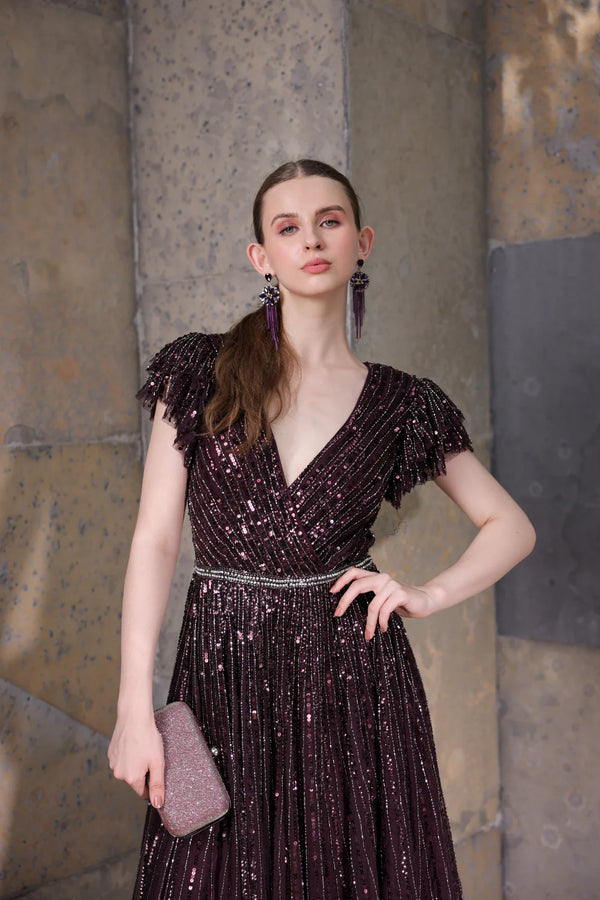 Model walking in blackberry sequin gown with tiered sleeves — showcasing shimmering embellishments and layered sleeve motion